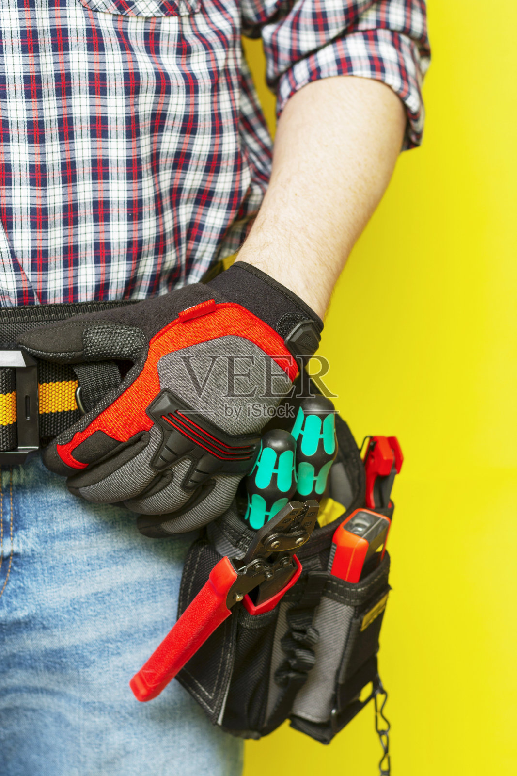 电工或专业施工人员在安装人员的皮带上，工具在黄色背景上。电工工具装在工人皮带上的黑色袋子里。带有文本空间的横幅照片摄影图片