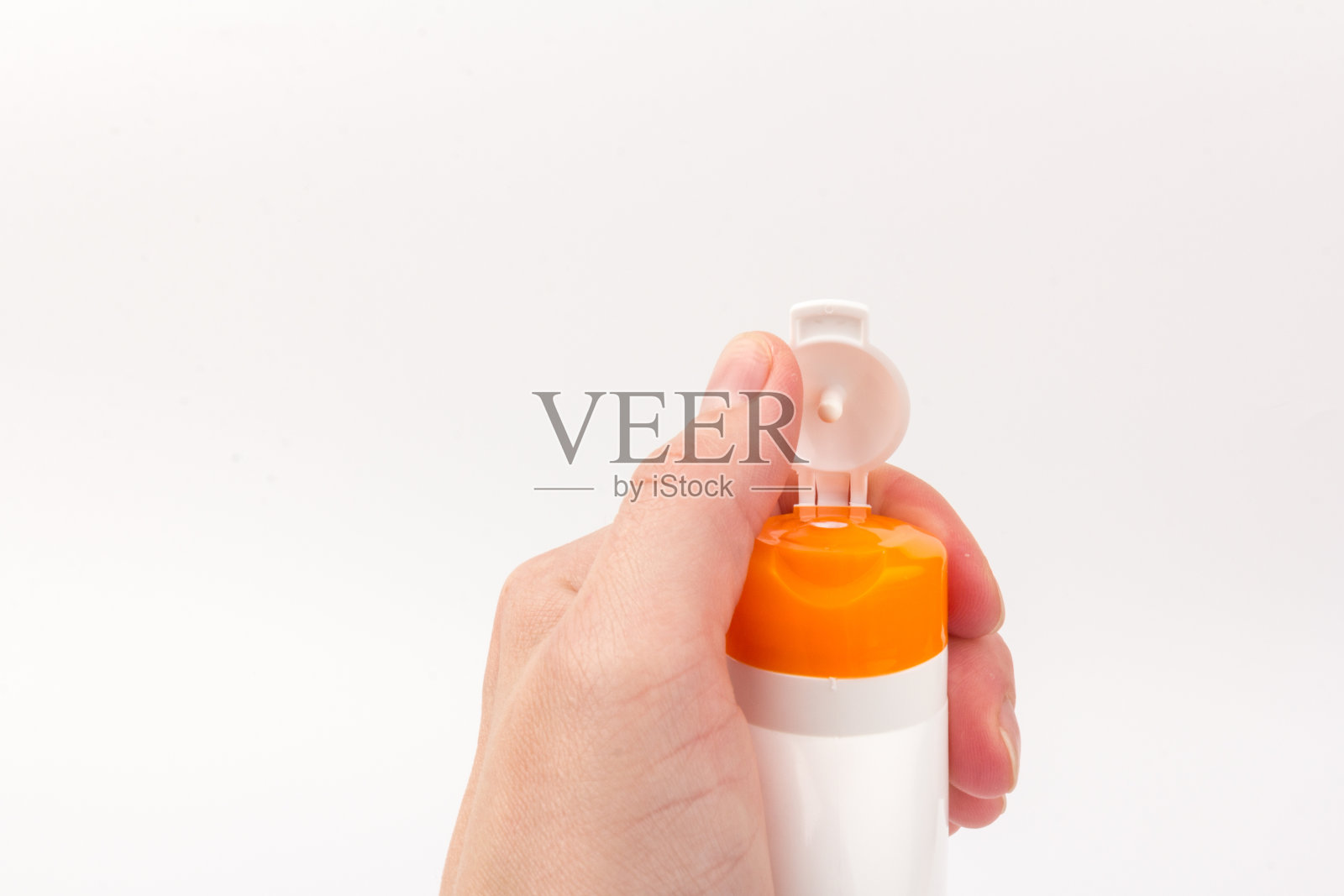 手拿防晒霜瓶，白色背景。健康理念和皮肤护理照片摄影图片