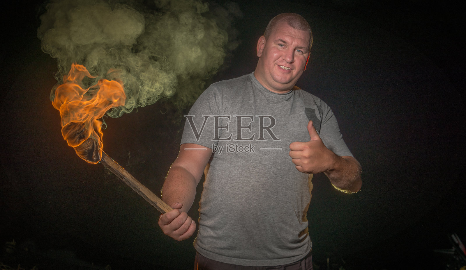 一个男人在夜里拿着燃烧的火把。照片摄影图片