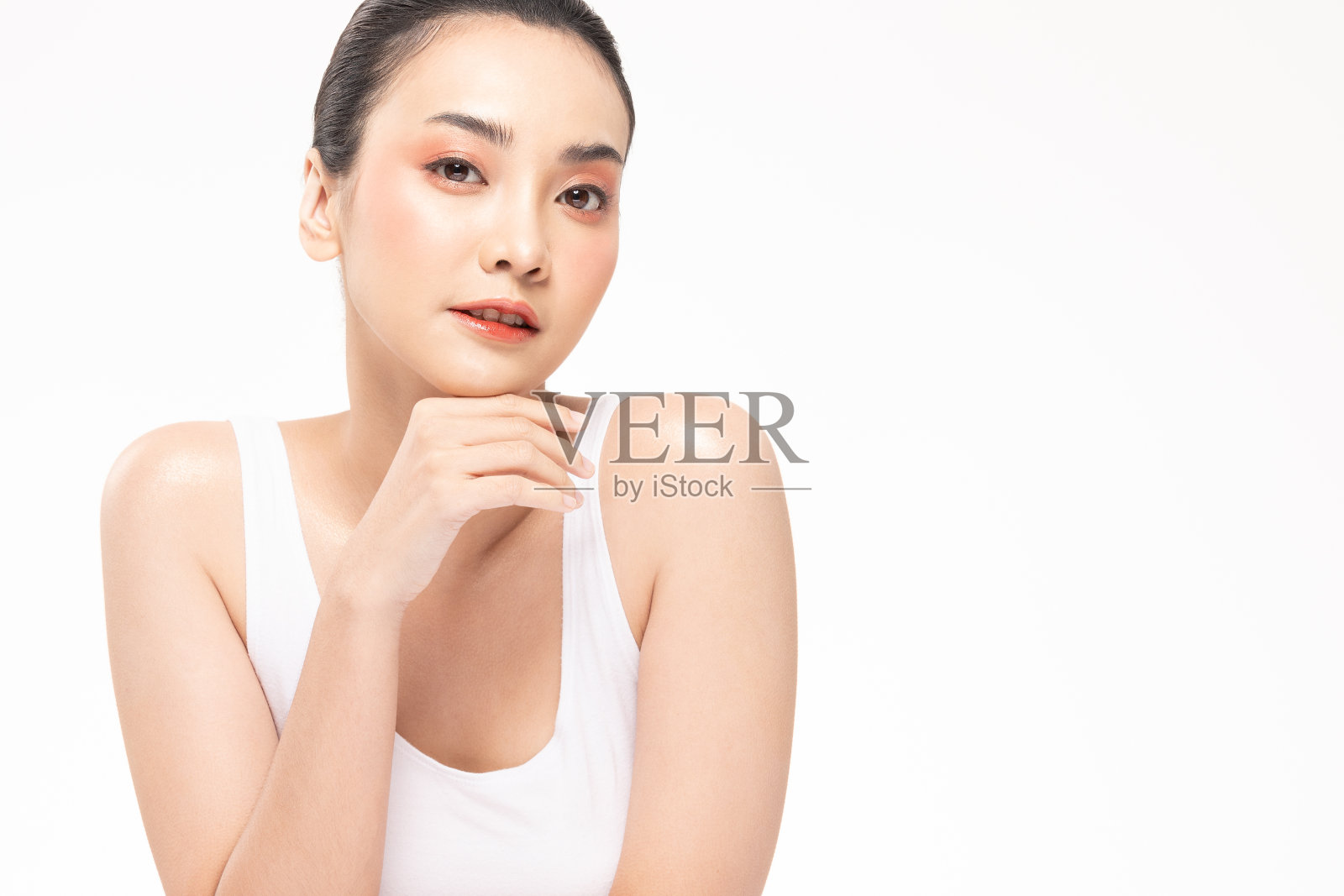 美丽的亚洲女性触摸柔软的下巴肖像脸与自然的皮肤和皮肤护理健康的头发和皮肤特写脸的美丽肖像。白色背景上的美丽概念。照片摄影图片