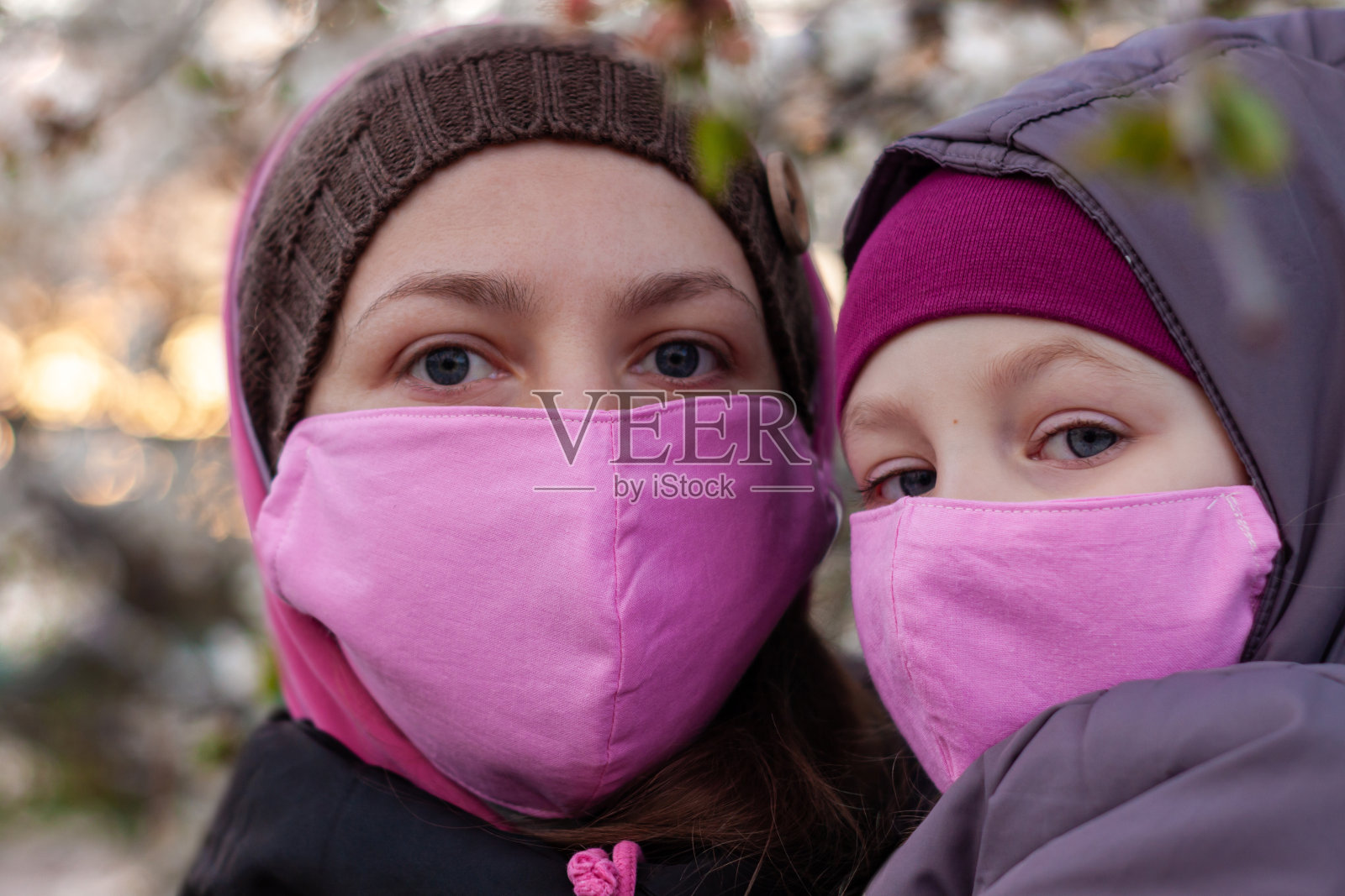 母亲和女儿戴着粉色防护口罩，以预防COVID-19冠状病毒病。停止流行手势。照片摄影图片