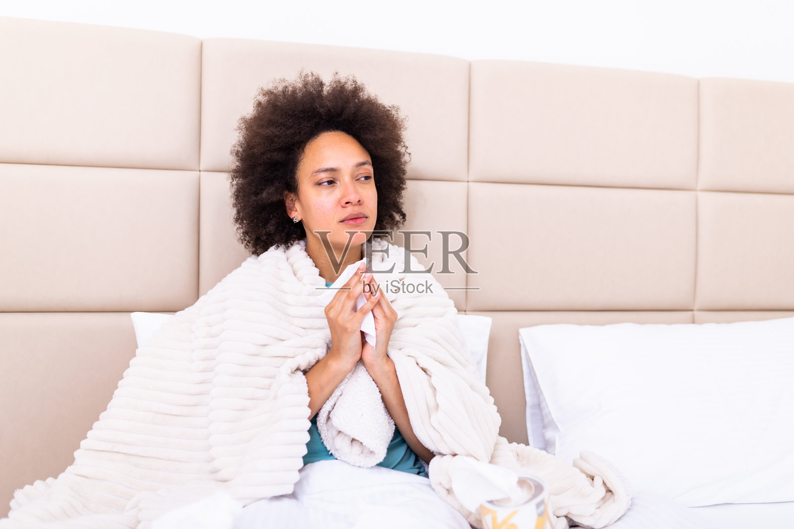 生病的非洲裔美国年轻女子坐在家里盖着温暖的毯子吹流鼻涕，生病不舒服的黑人女孩感到不健康的感冒有流感症状，患流感高烧照片摄影图片