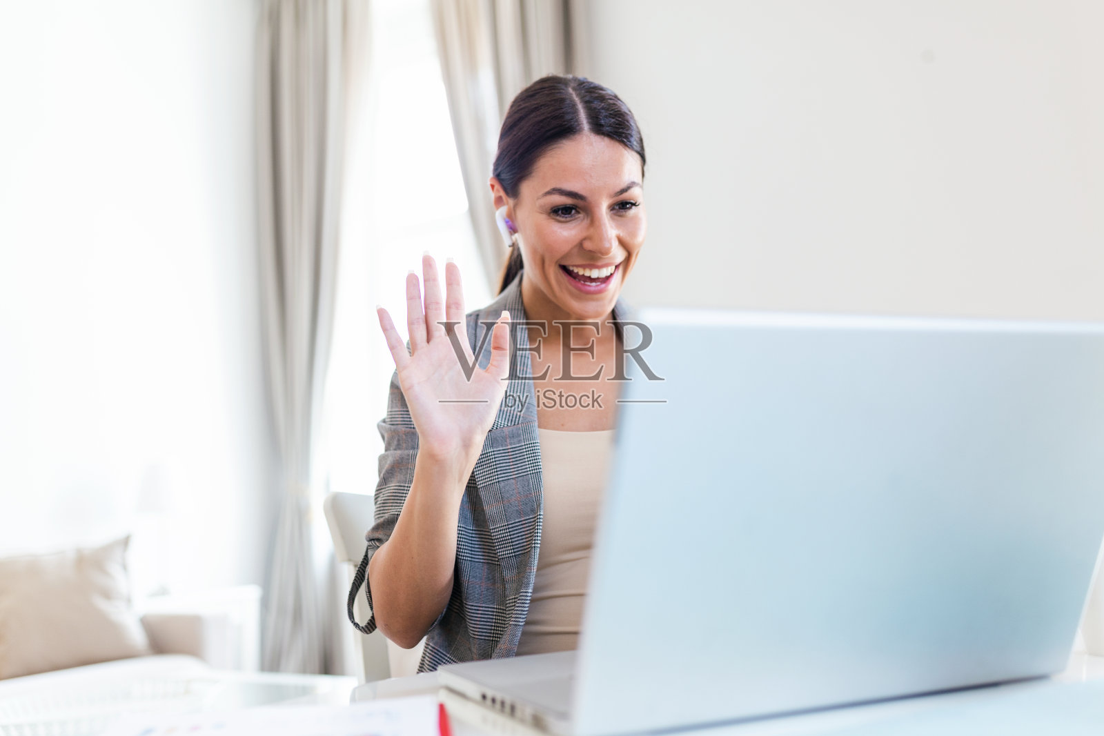 快乐的年轻女子戴着耳机讲话，看着笔记本做笔记，女学生通过视频电话会议讲话，女教师培训师通过网络摄像头进行辅导，在线培训，电子辅导的概念照片摄影图片