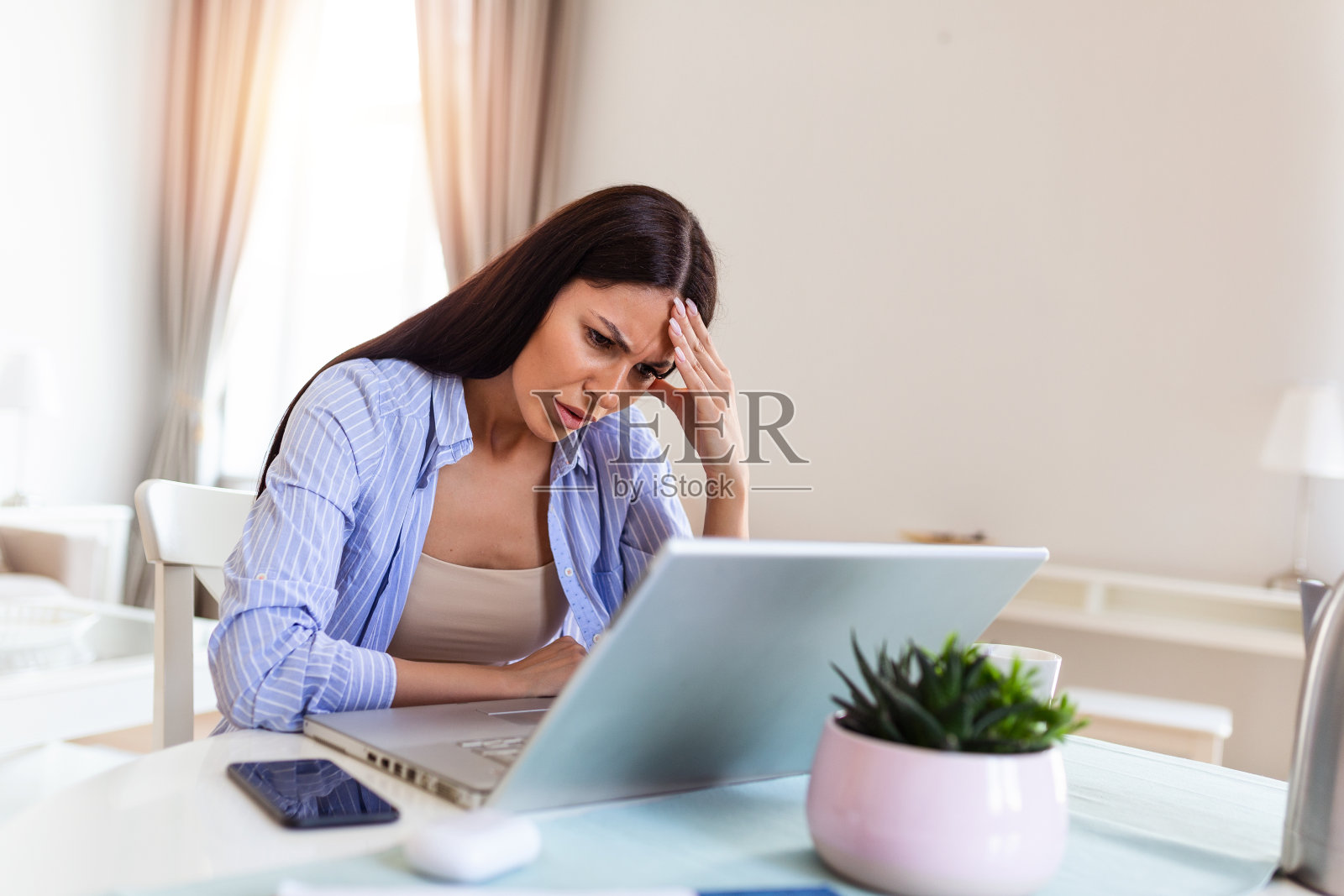 一名沮丧的年轻女性每天坐在办公桌前的笔记本电脑前忍受着慢性头痛，在线治疗，预约医疗咨询，电磁辐射，病假工资照片摄影图片