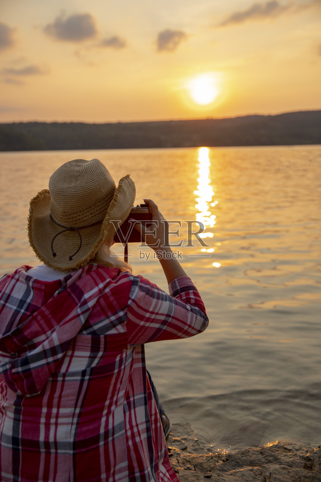 在河岸上的旅行者在拍摄日落。照片摄影图片