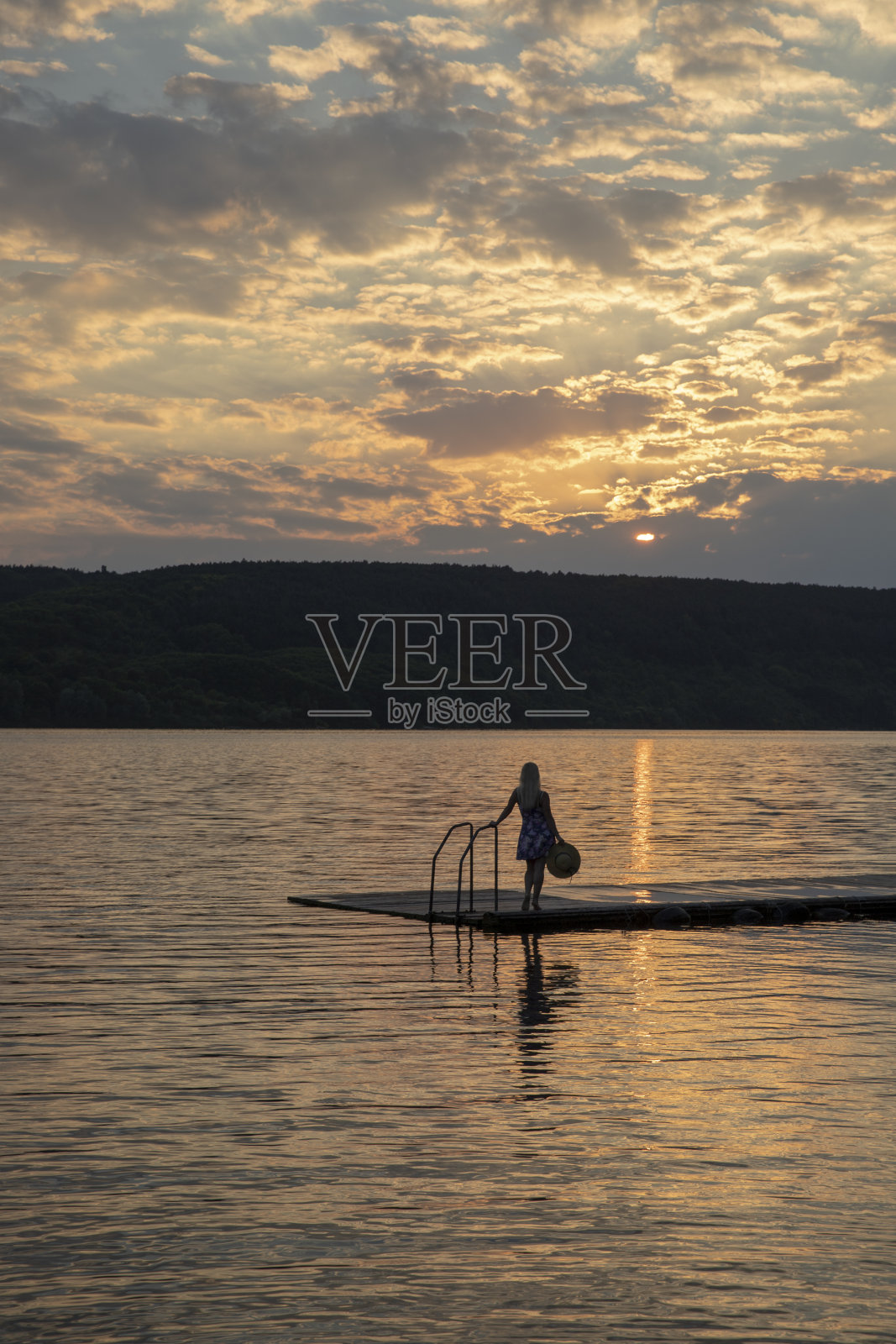 站在码头上的女孩在日落时在码头上的剪影照片摄影图片