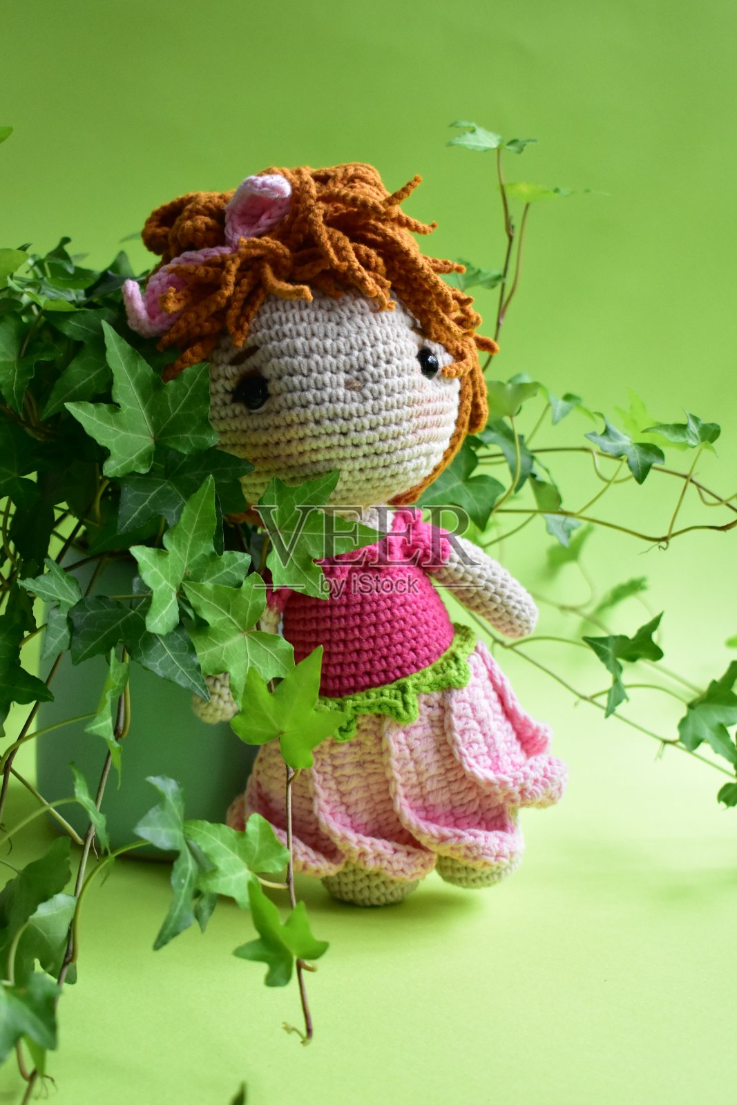 可爱的钩针娃娃以常春藤(Hedera Helix)树叶为背景，绿色柔和，淡绿色，生态友好，植物学，环保，新生活，和平的主题，复古花园照片摄影图片