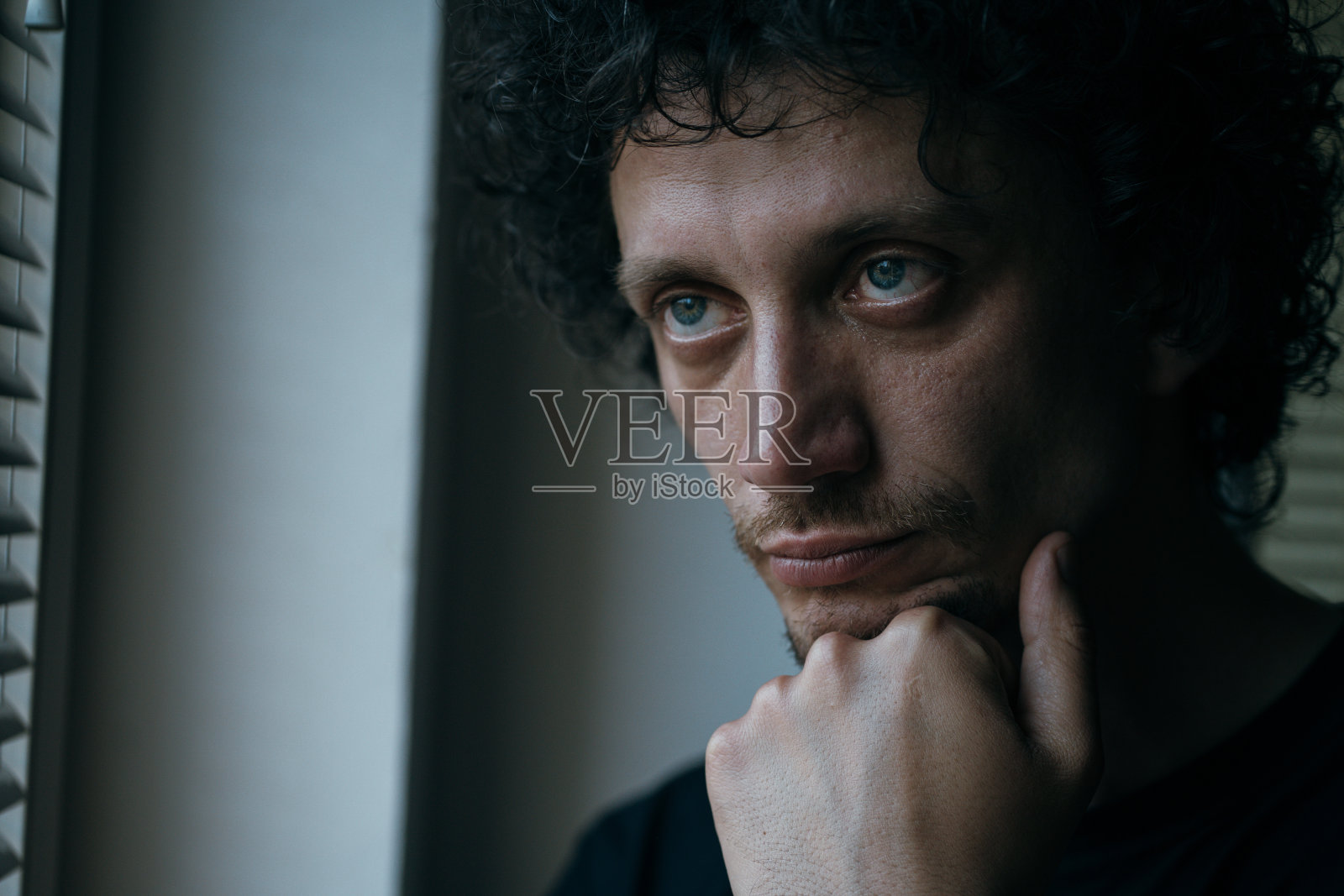 一个悲伤的男人在看窗外照片摄影图片