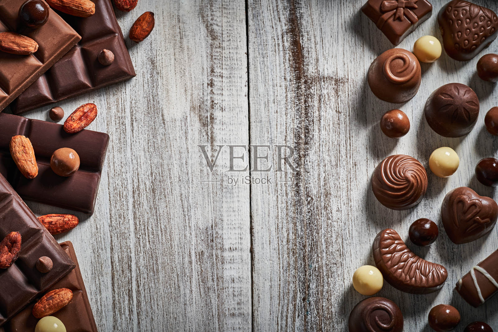 各式各样的巧克力棒，巧克力松露，坚果和可可豆放在白色的木制乡村桌子上照片摄影图片