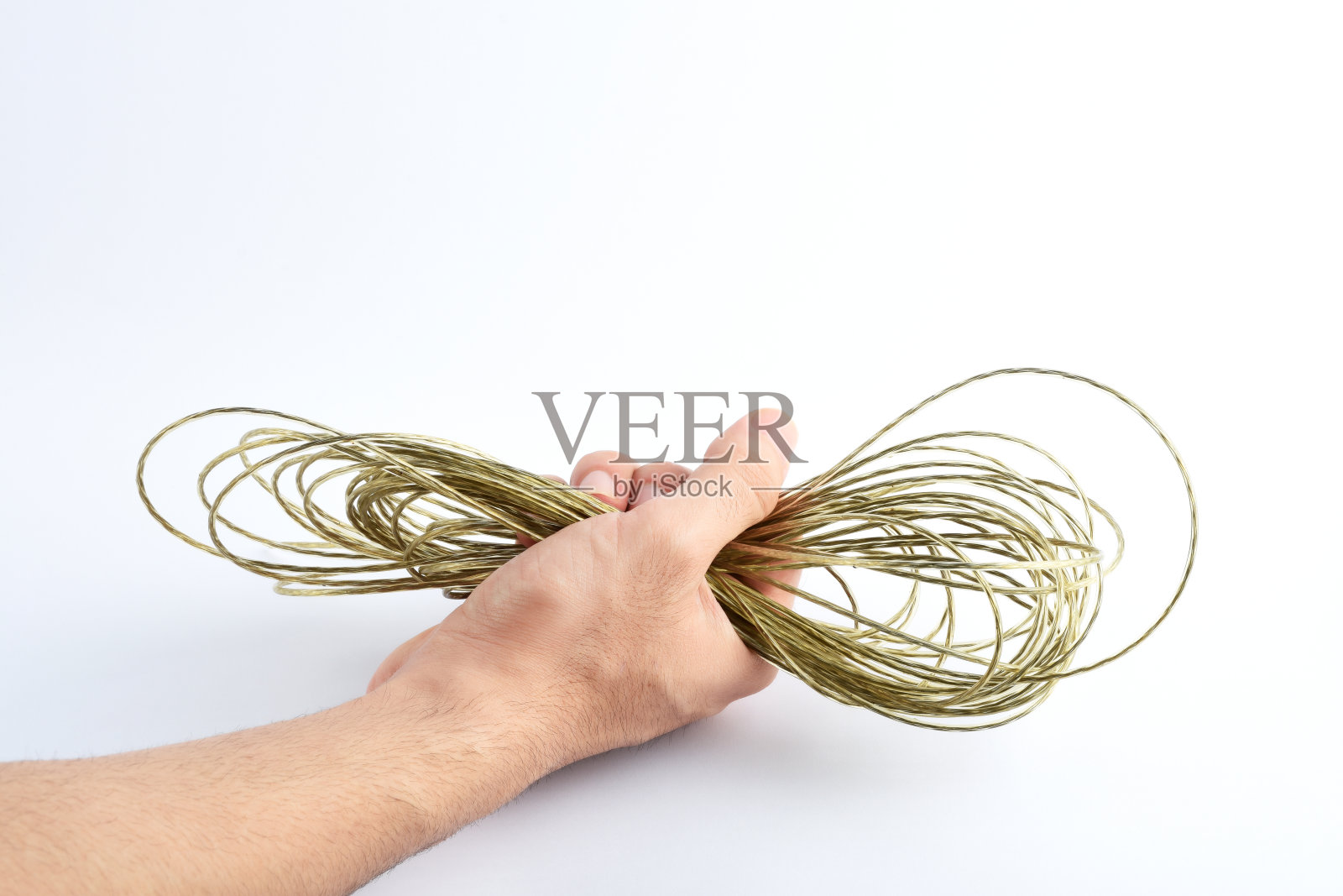 白色背景上，一只男性的手握着涂有塑料的金属线照片摄影图片