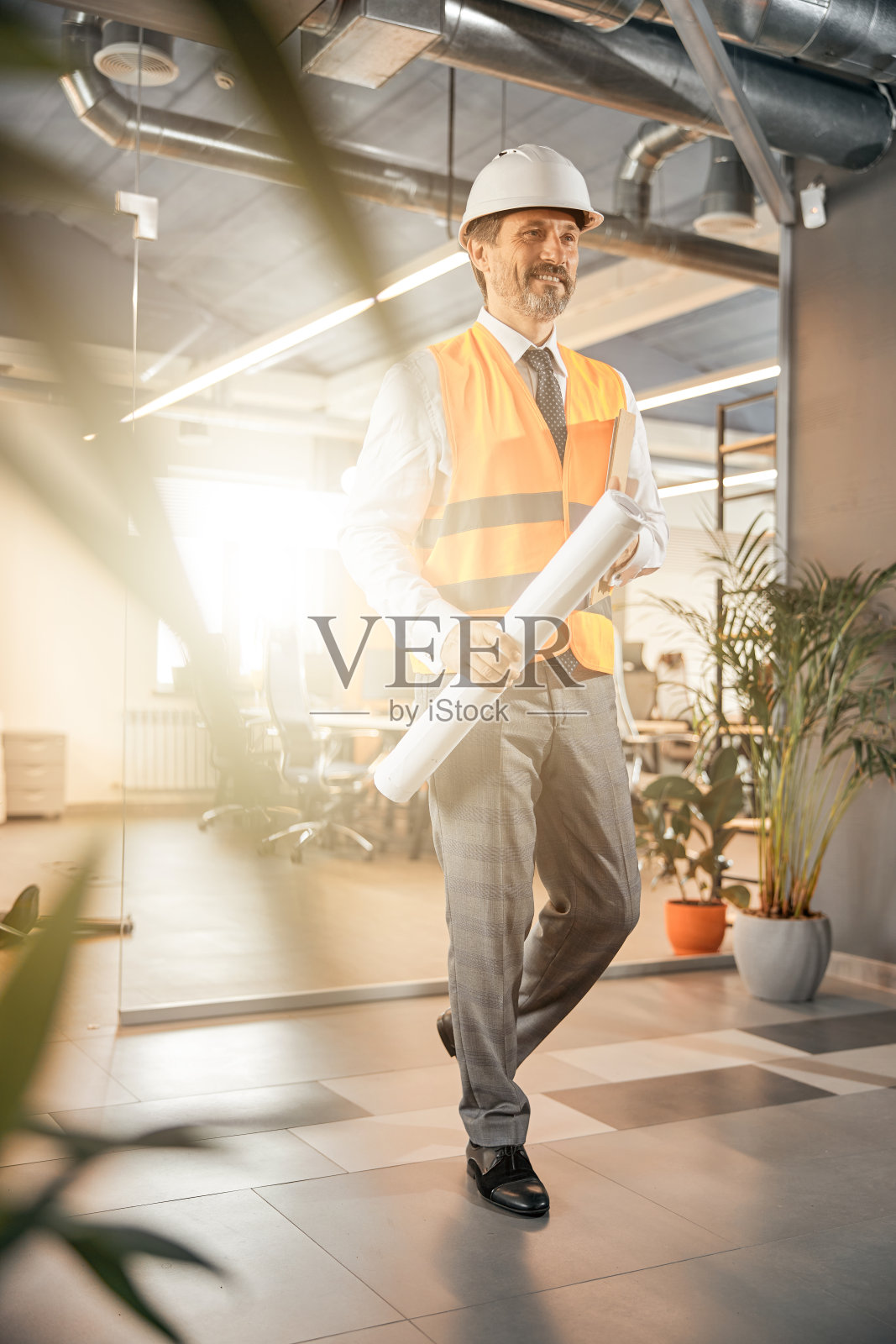 建筑工程师把办公室蓝图靠在脚手架上照片摄影图片