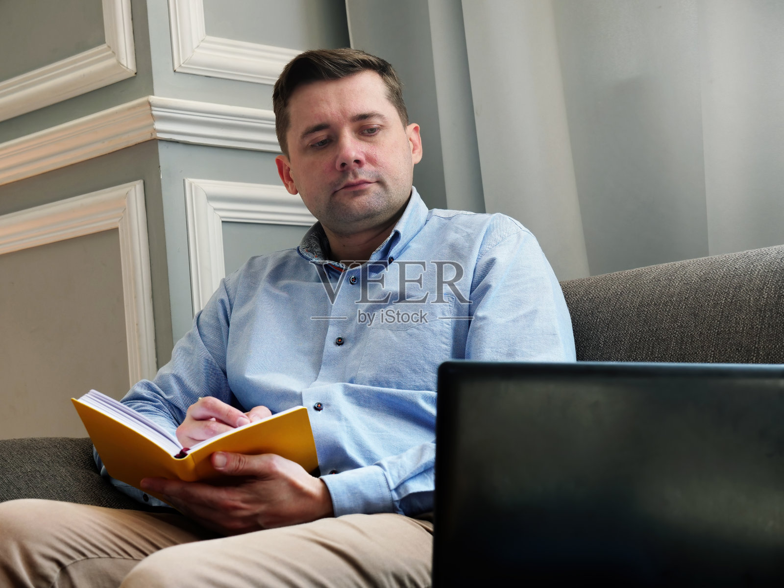 居家办公一个男人坐在沙发上检查数据并工作。照片摄影图片