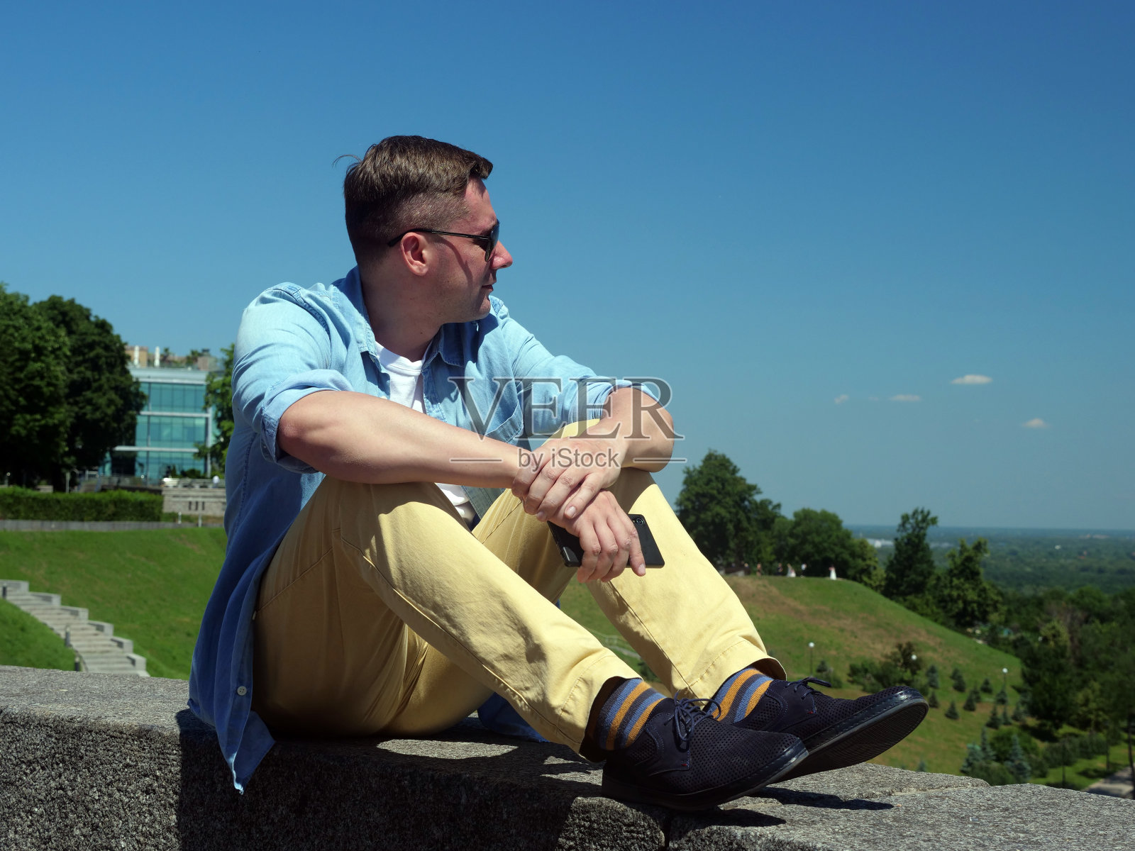 夏天放松。这个人坐在公园里看城市。照片摄影图片