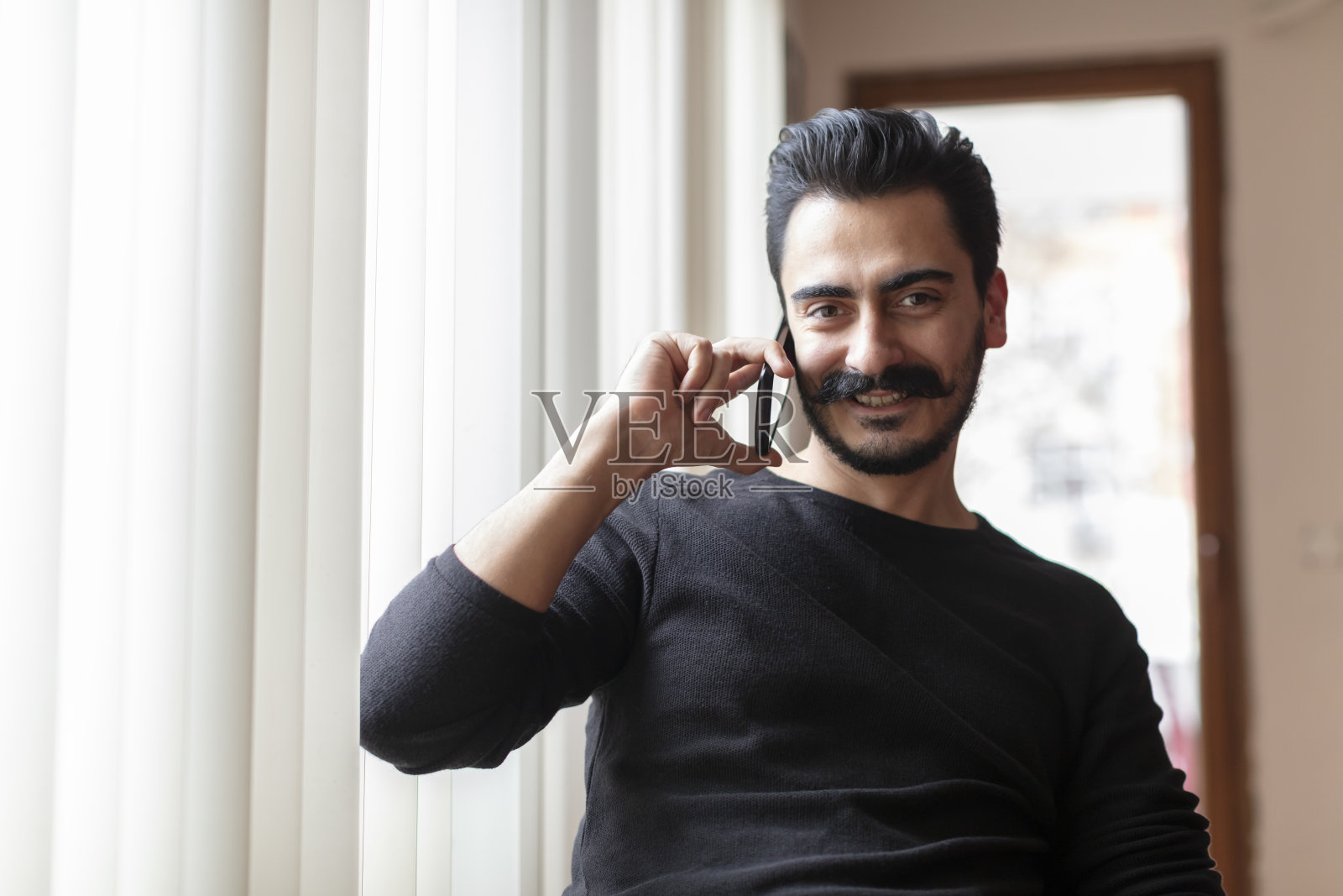 留着胡须的年轻男人在用智能手机交谈照片摄影图片