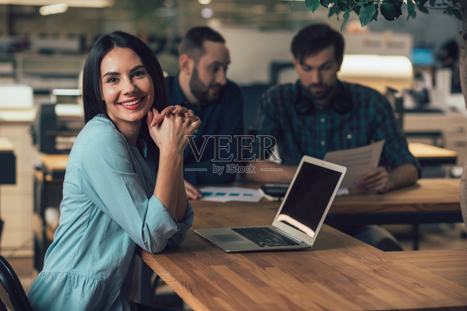 快活的女士在她的工作场所摆姿势，微笑着照片摄影图片