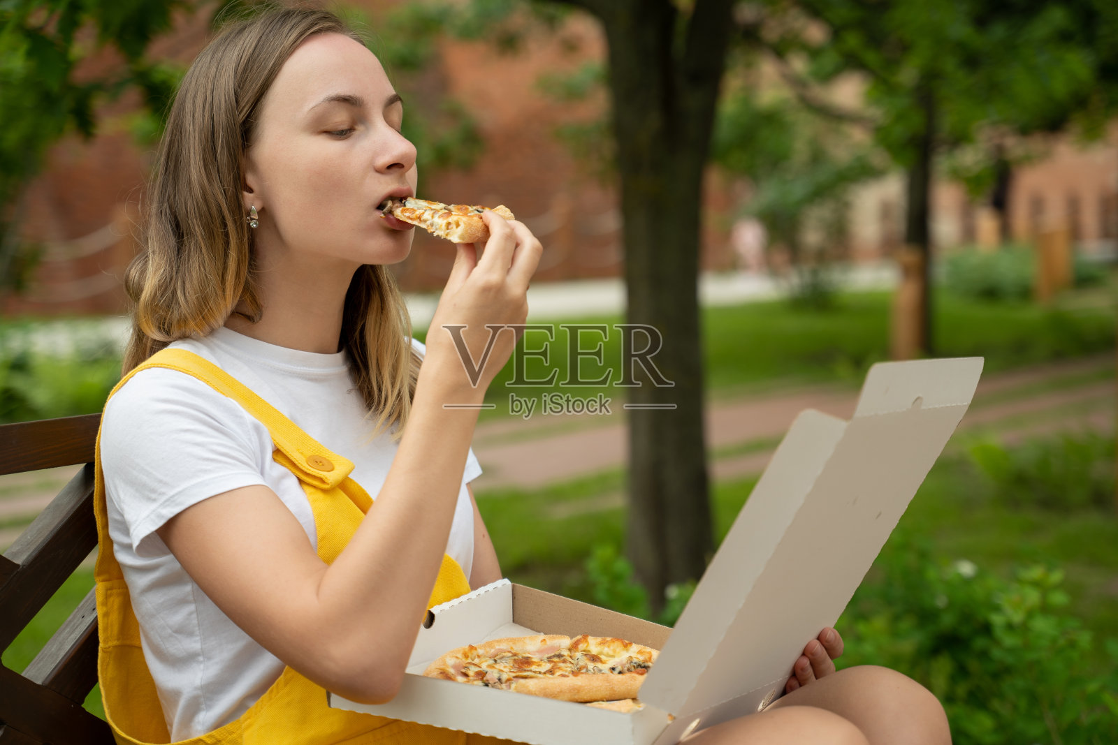 一个年轻女人在街上吃披萨照片摄影图片