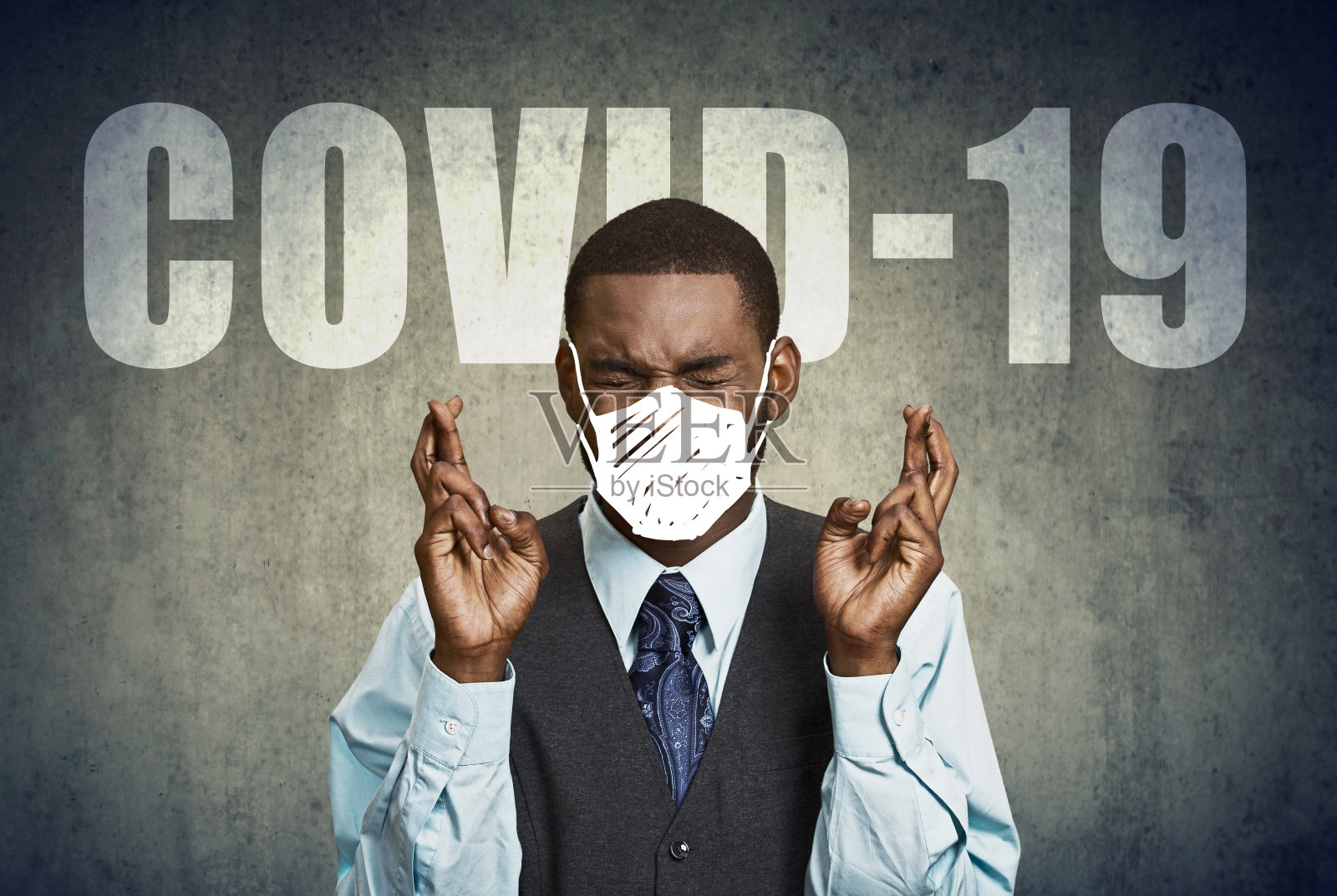 一名害怕冠状病毒的焦虑男子的肖像，双手交叉，戴着防护口罩照片摄影图片