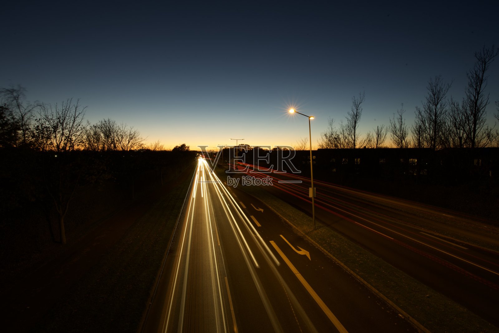 夕阳下的道路上模糊了汽车的前灯和尾灯。照片摄影图片