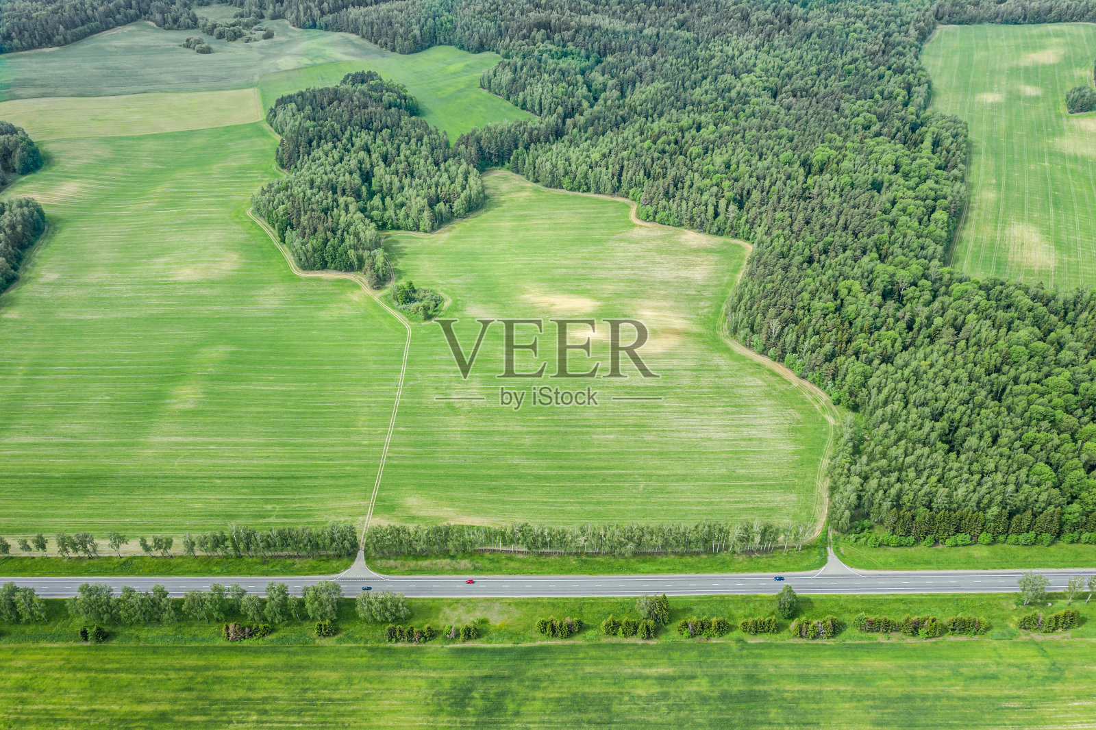 这是白俄罗斯乡间小路的鸟瞰图，上面有车辆穿梭于农田之间。鸟眼视图照片摄影图片