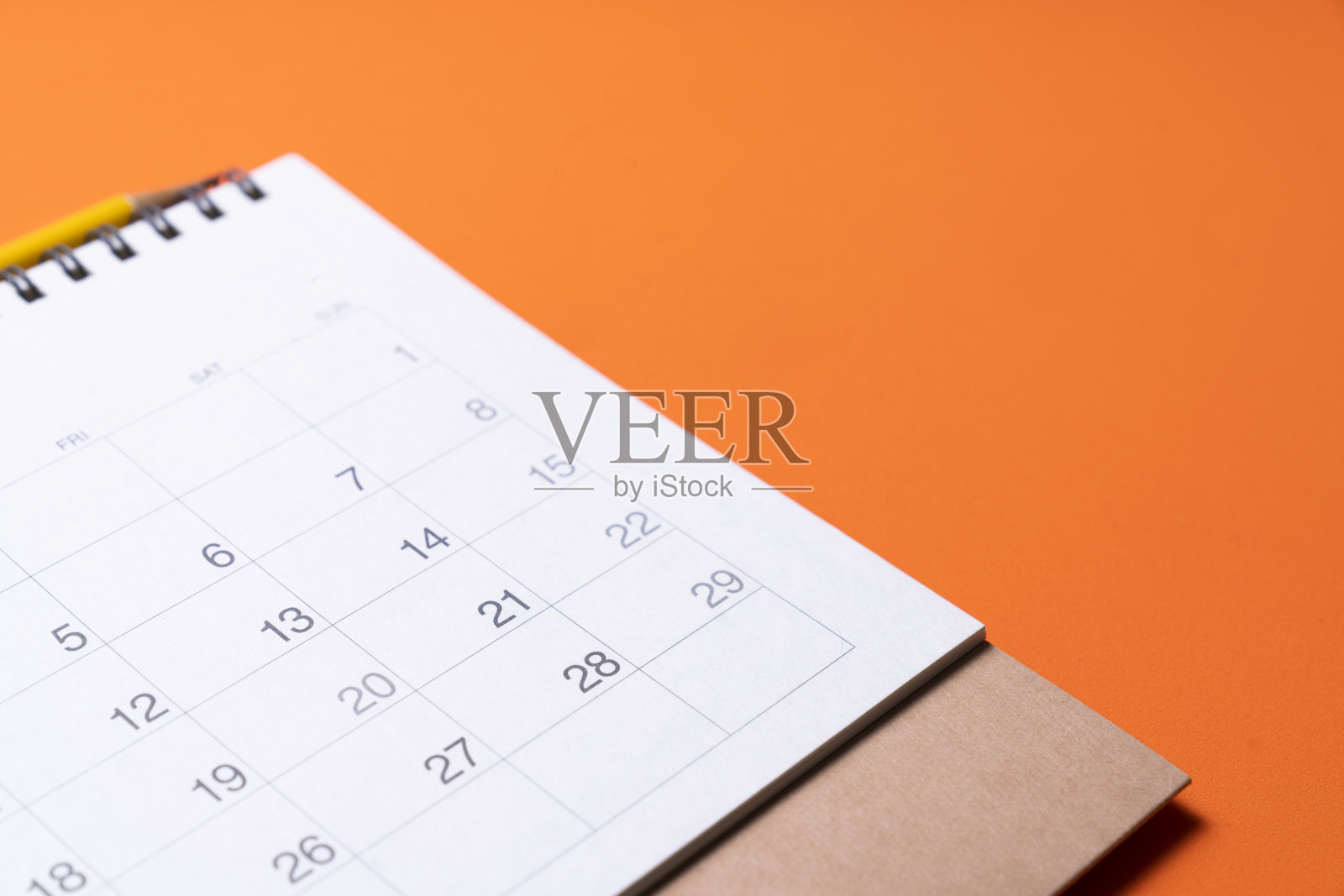 近距离的日历放在橙色的桌子上作为背景，计划商务会议或旅行计划的概念照片摄影图片