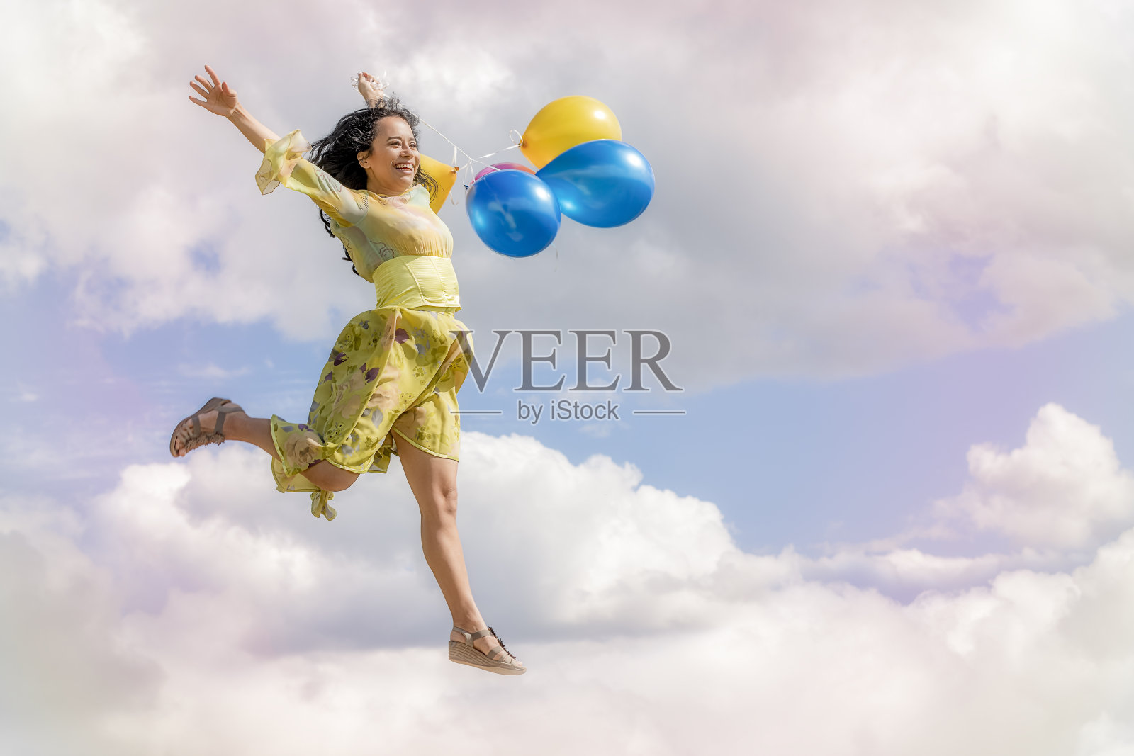 快乐的女孩手里拿着气球在云层里跳照片摄影图片