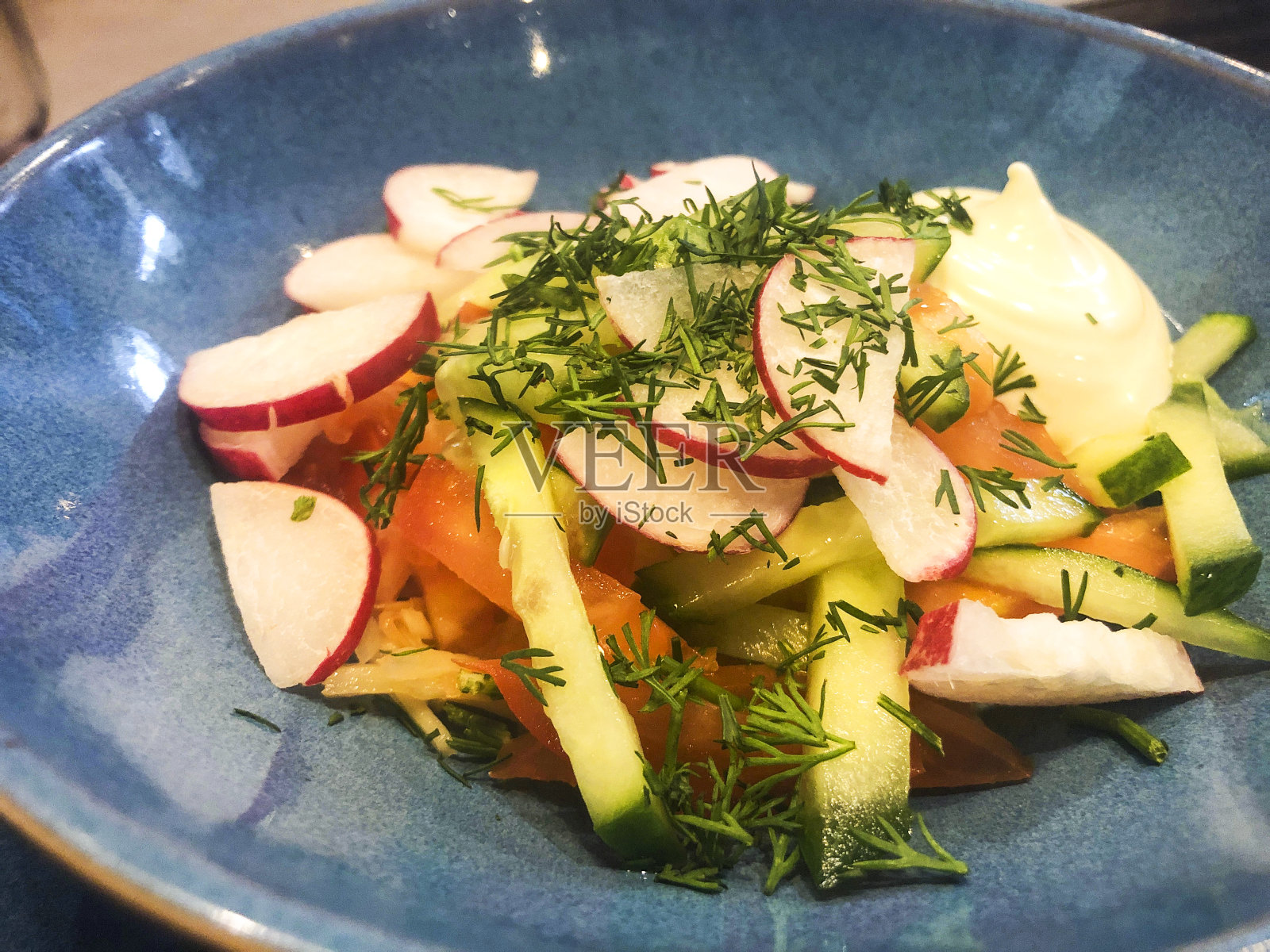 蓝色盘子里的新鲜蔬菜沙拉。照片摄影图片