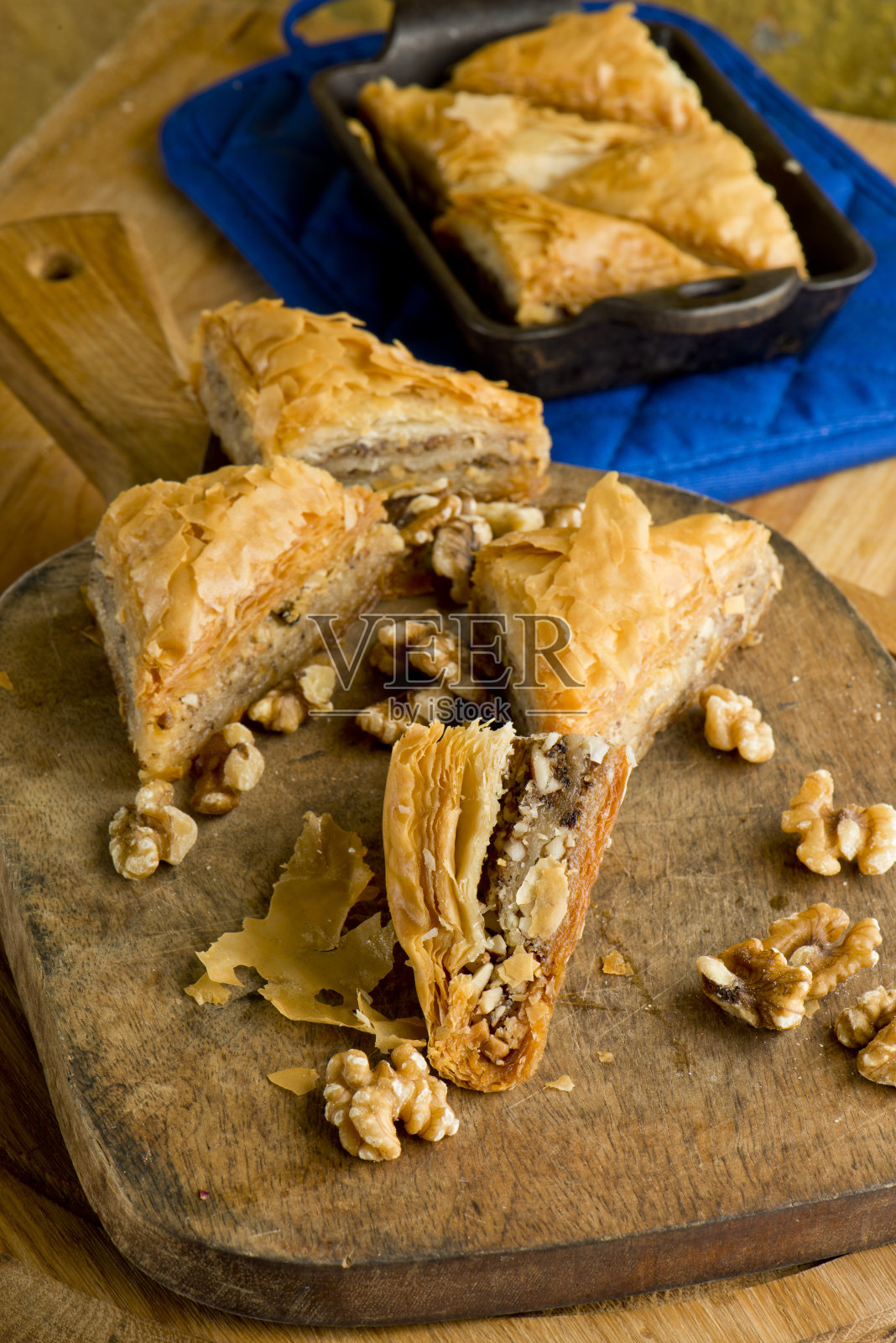 果仁蜜，用核桃和开心果做的。经典的希腊或意大利面包店或糕点店的最爱。菲洛面团，蜜饯核桃，开心果和蜂蜜。饼干，鲜奶油，蛋糕，巧克力奶油，鸡蛋和香草豆。照片摄影图片