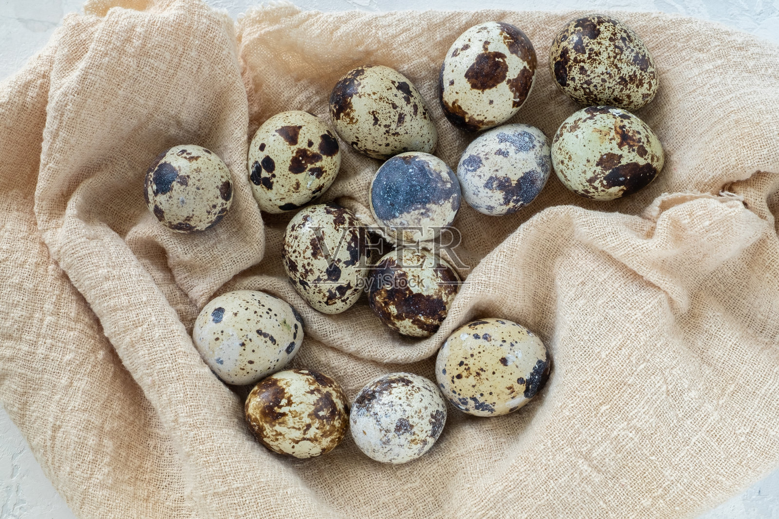 收起许多新鲜的鹌鹑蛋躺在一块轻薄的亚麻布餐巾上。照片摄影图片