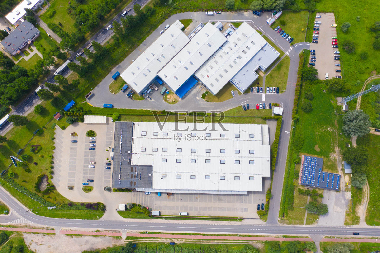 屋顶上有太阳能电池板的现代仓库鸟瞰图。从无人机角度看工业城区的物流中心。背景纹理的概念。照片摄影图片