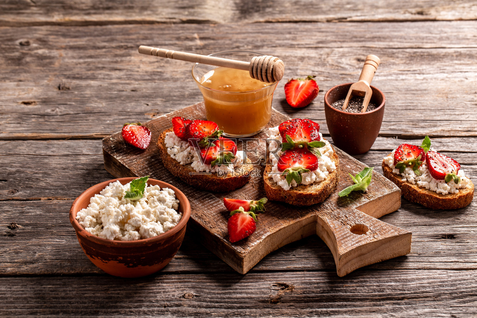 夹有草莓、乳清干酪、薄荷、蜂蜜、木纹背景的三明治照片摄影图片