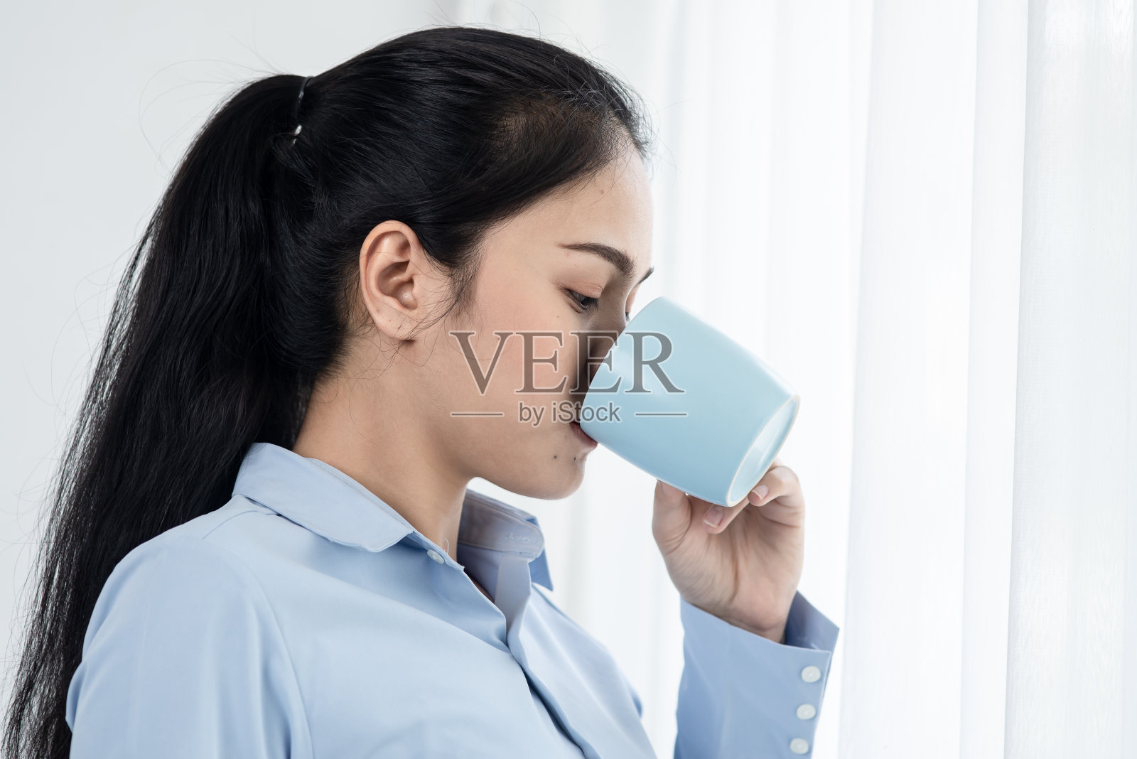 亚洲商务女性在早上喝咖啡靠近窗口，生活方式的概念。照片摄影图片