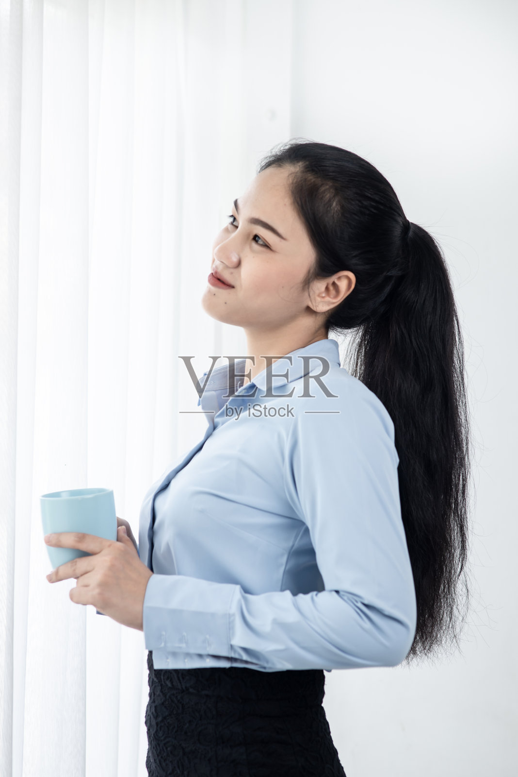 亚洲商务女性在早上喝咖啡靠近窗口，生活方式的概念。动态模糊。照片摄影图片