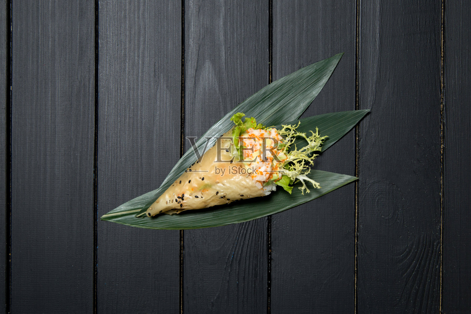 日本寿司天木配虎虾、米饭、飞鱼卵、牛油果和竹叶上的海草沙拉照片摄影图片