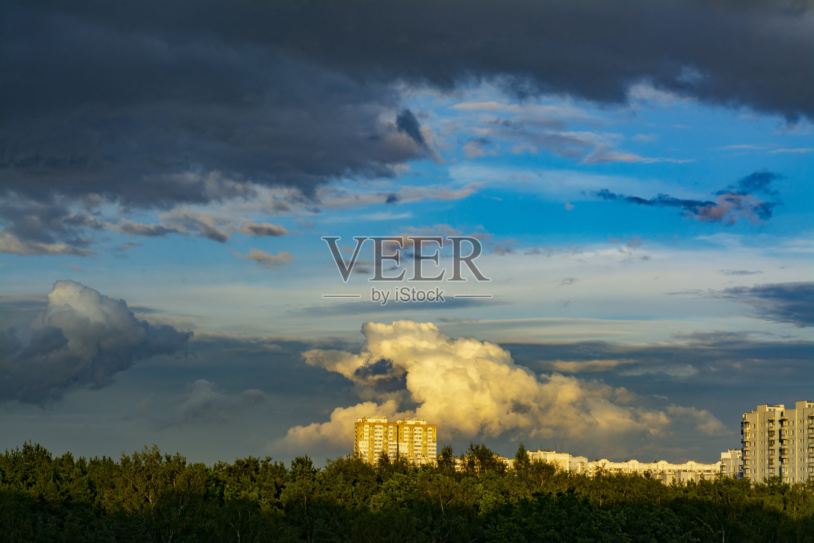 多层住宅建筑后面的森林在日落的背景下，风景如画的云照片摄影图片