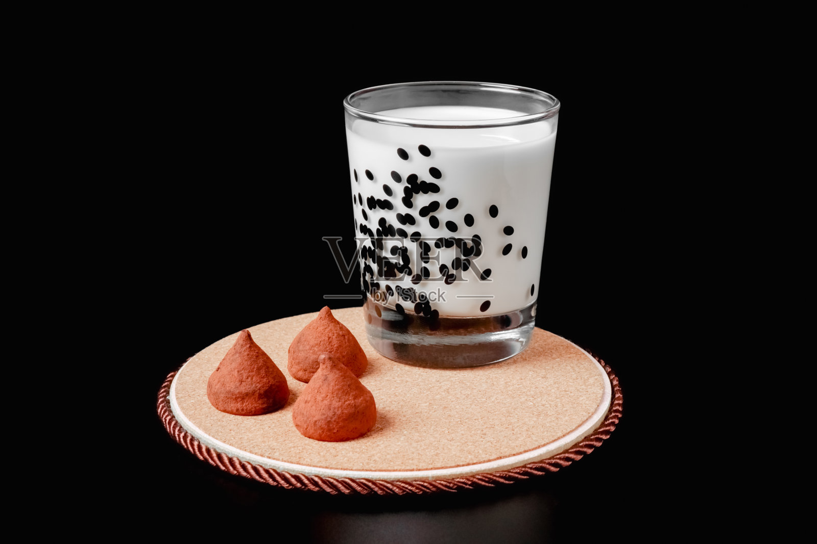 一杯牛奶和一块松露糖，背景是黑色。健康食品。隔离照片摄影图片