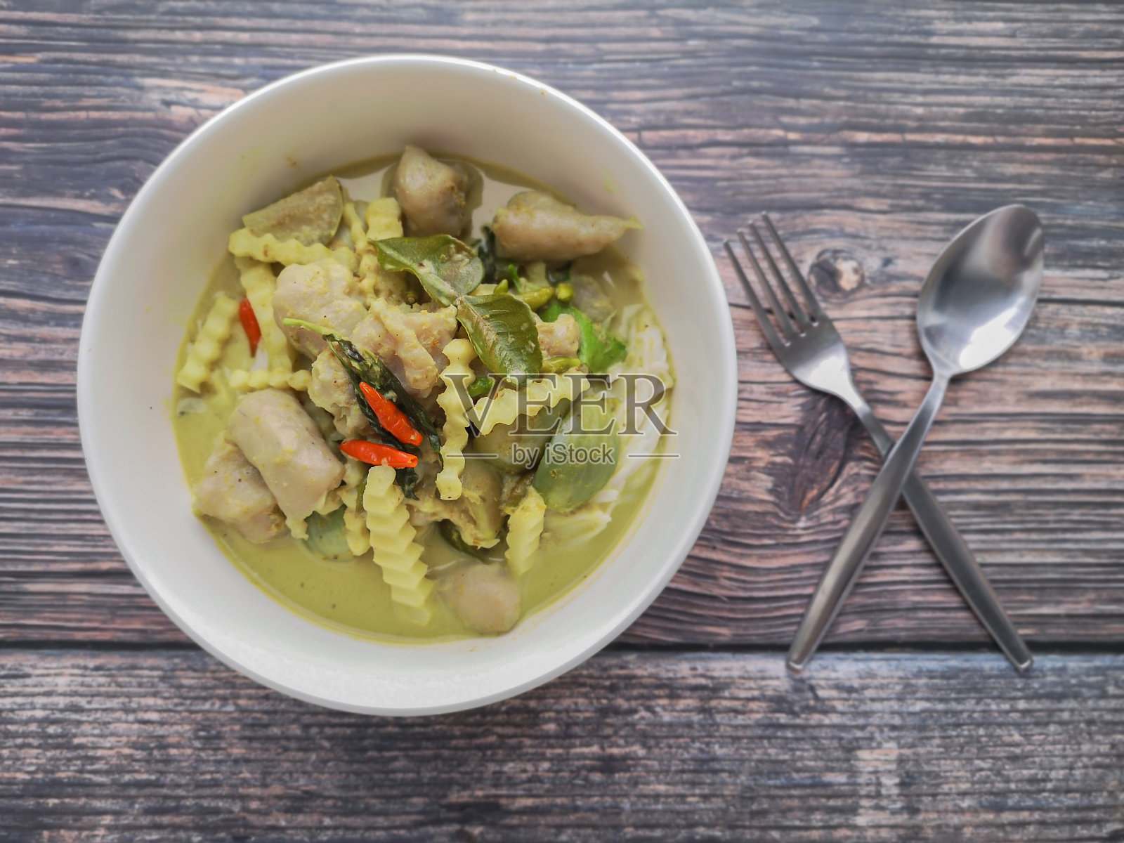 绿色咖喱与鱼丸和椰子芽在白色碗木背景。泰国菜的名字叫“keng Khiaw-Wan”。照片摄影图片