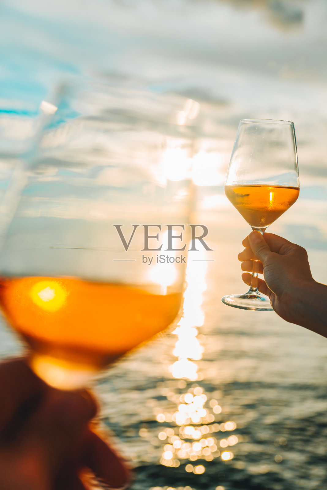 一对情侣在海边的日落上休息，喝着葡萄酒照片摄影图片