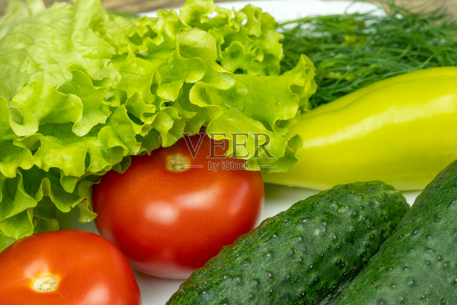 白色的盘子里放着新鲜多汁的蔬菜:新鲜的辣椒，西红柿，黄瓜，生菜，莳萝照片摄影图片