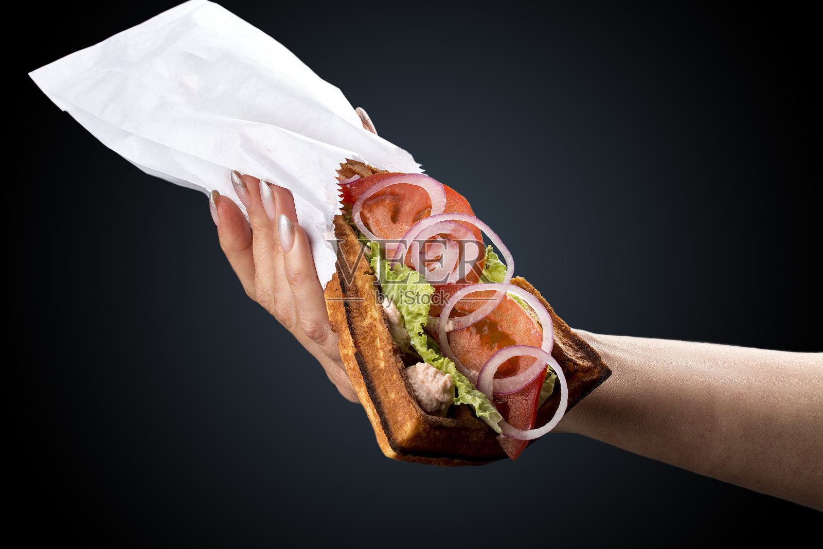 比利时华夫饼配金枪鱼，沙拉和西红柿。手在黑暗的背景上照片摄影图片