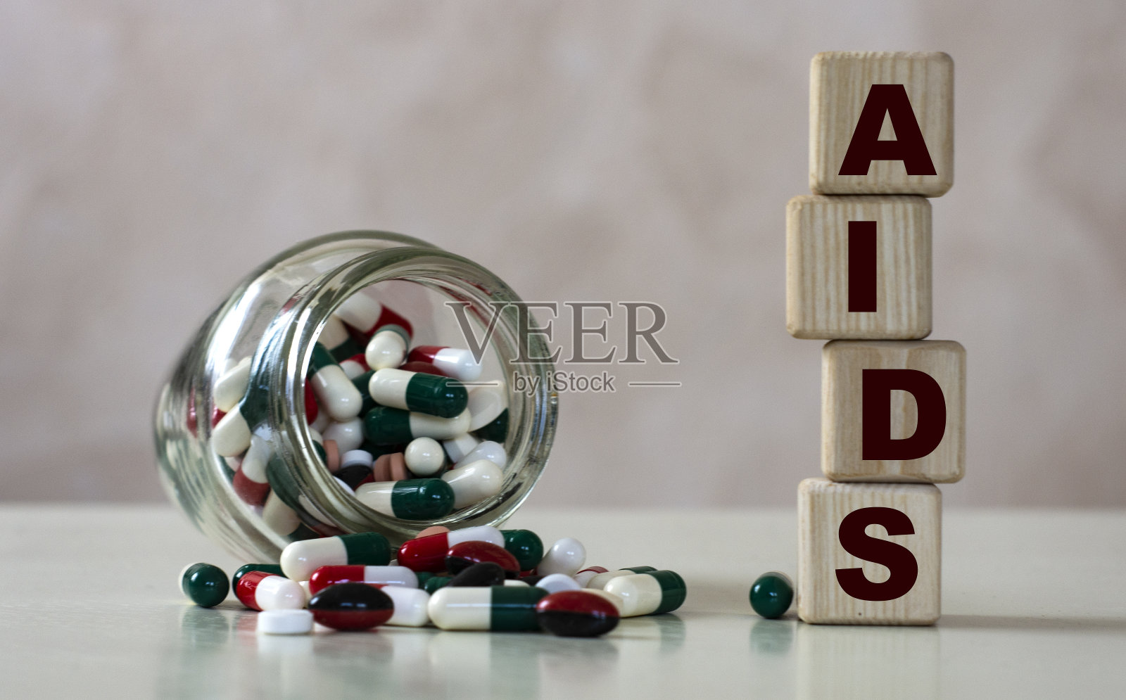 艾滋病(获得性免疫缺陷综合征)的简写在木方上，背景是一罐药丸照片摄影图片