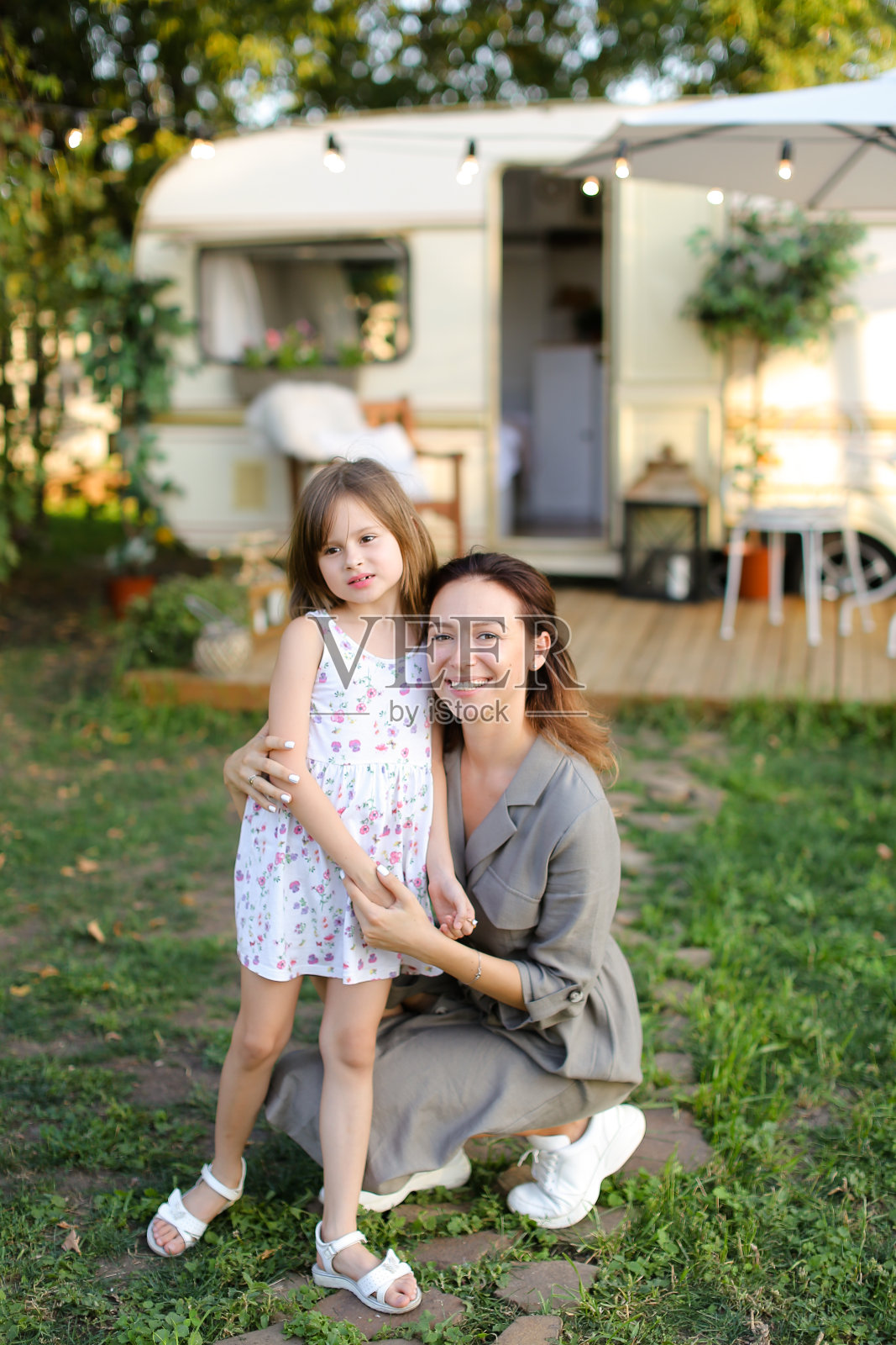年轻女子在车轮上的房子附近亲吻女儿照片摄影图片