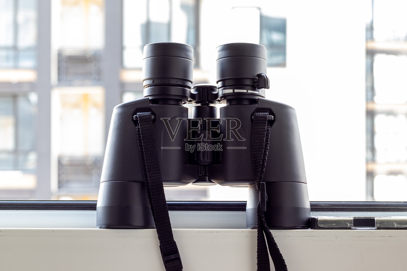 一种黑色的双筒望远镜，以模糊的窗户背景为背景，观察邻居、环境或自然。有选择性的重点。特写视图照片摄影图片