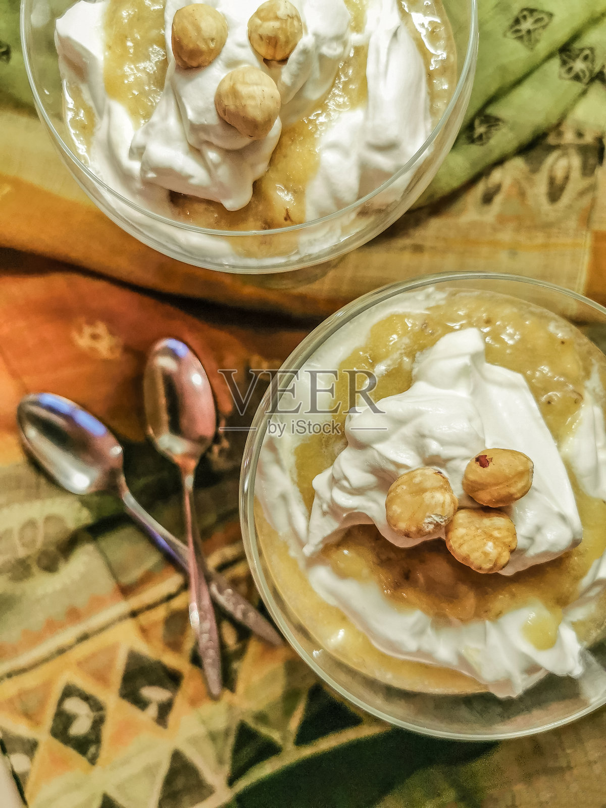 白玉兰香蕉布丁配芝麻，蜂蜜，柠檬，坚果和鲜奶油的玻璃杯，放在装饰的桌子上照片摄影图片