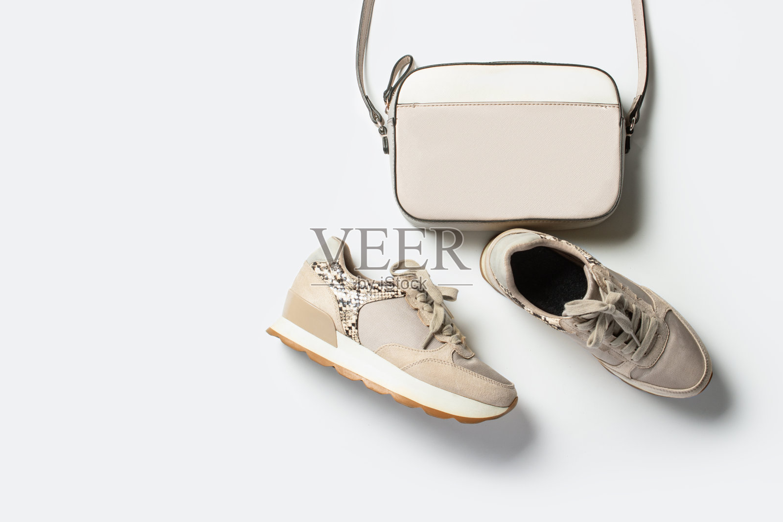女士的米色运动鞋和斜挎包在一个浅背景。平躺，俯视图照片摄影图片