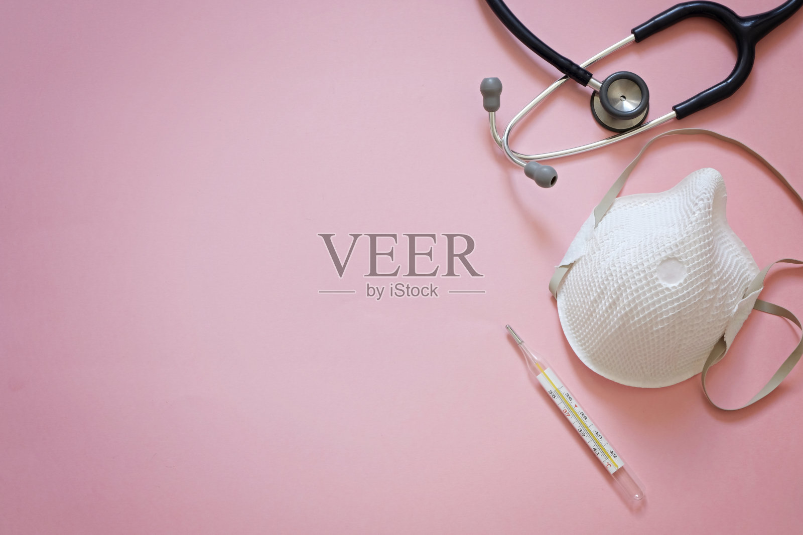 关于冠状病毒流行的粉红色背景与听诊器，医用口罩和温度计与拷贝空间照片摄影图片