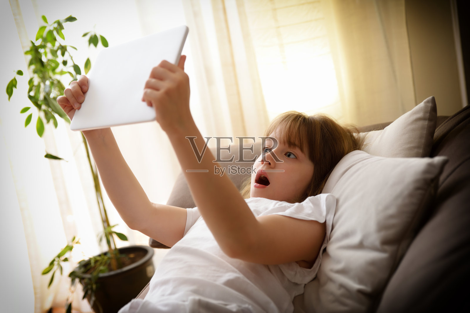 惊恐的女孩在家里看平板电脑上的有害内容照片摄影图片