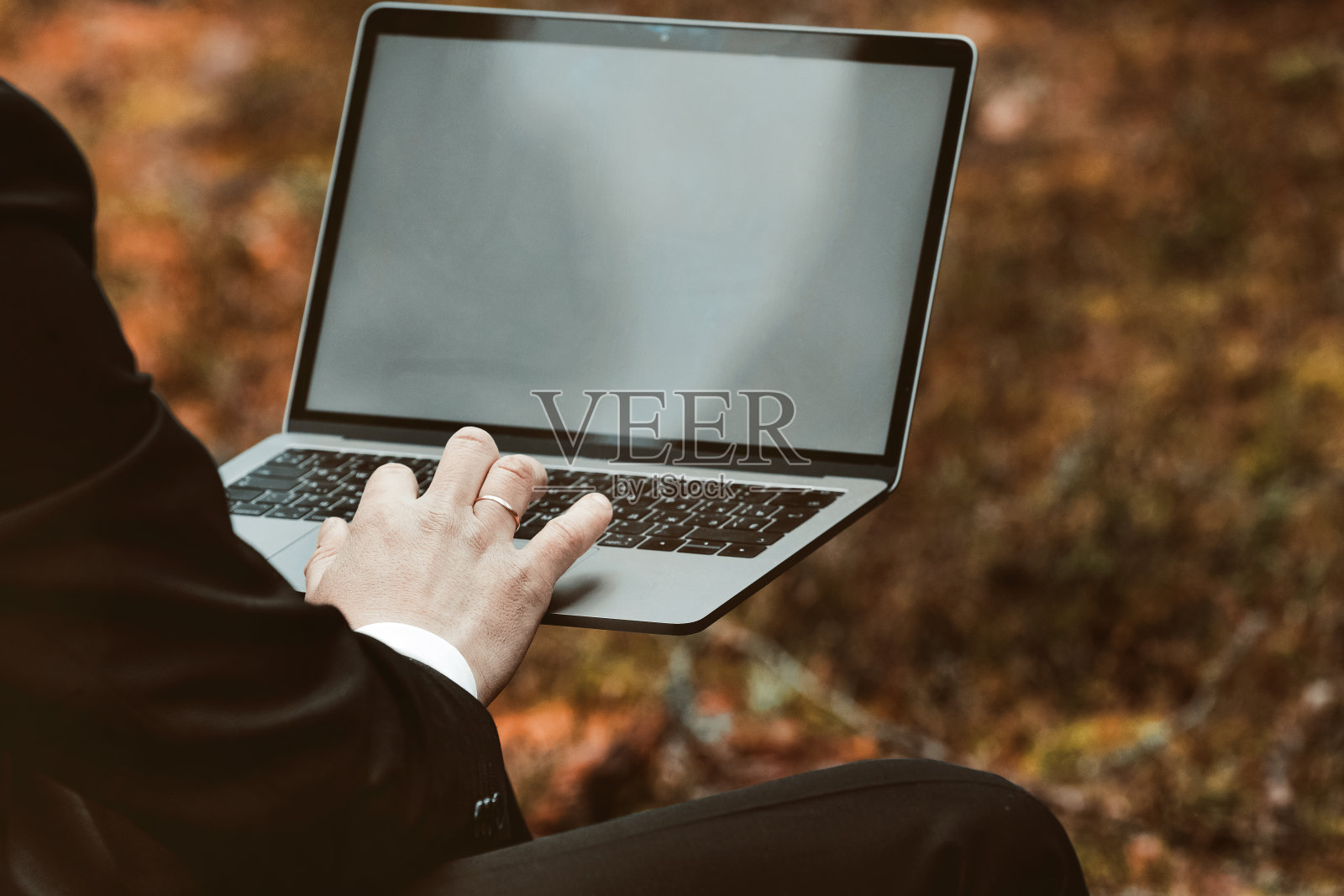 远程工作。网上的视频链接。一个在树林里的人用笔记本电脑和智能手机工作。照片摄影图片