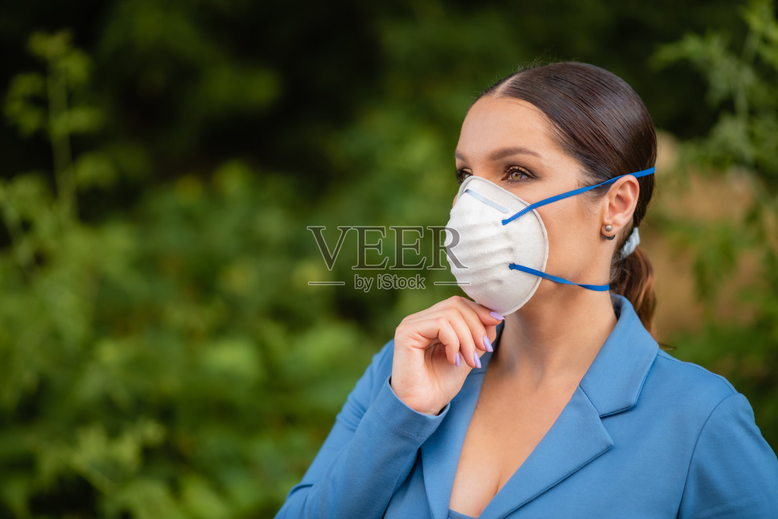 一个漂亮的女人站在街上脸上戴着纳米纤维制成的医用口罩。冠状病毒和Covid-19防护照片摄影图片