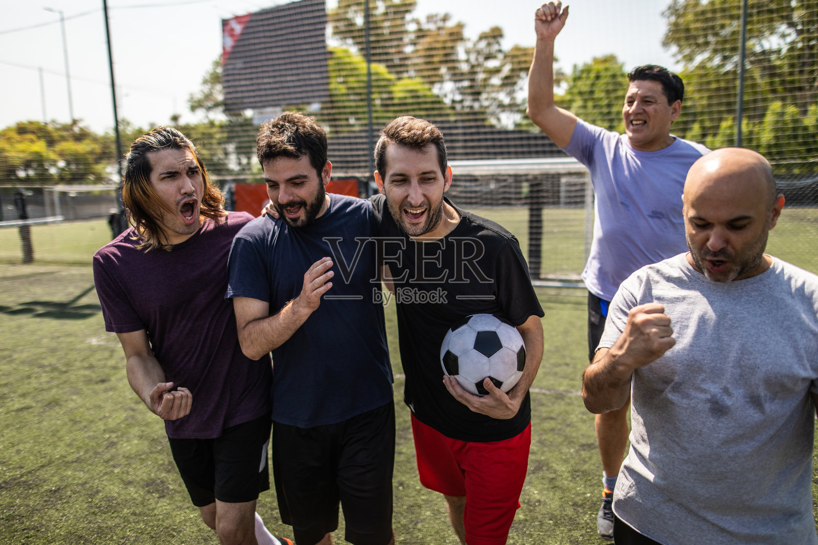 快乐的朋友们在足球场庆祝胜利照片摄影图片