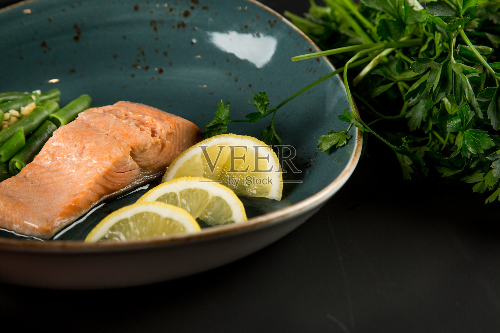 一块红色的鱼，豆子和柠檬在盘子里，旁边是一束欧芹照片摄影图片